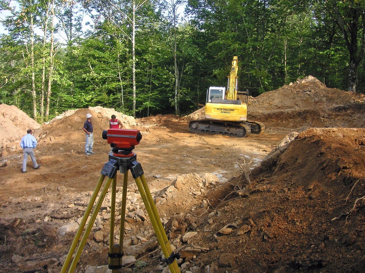 Construction workers, a land mover and surveying equipment prepare a site for potential development.