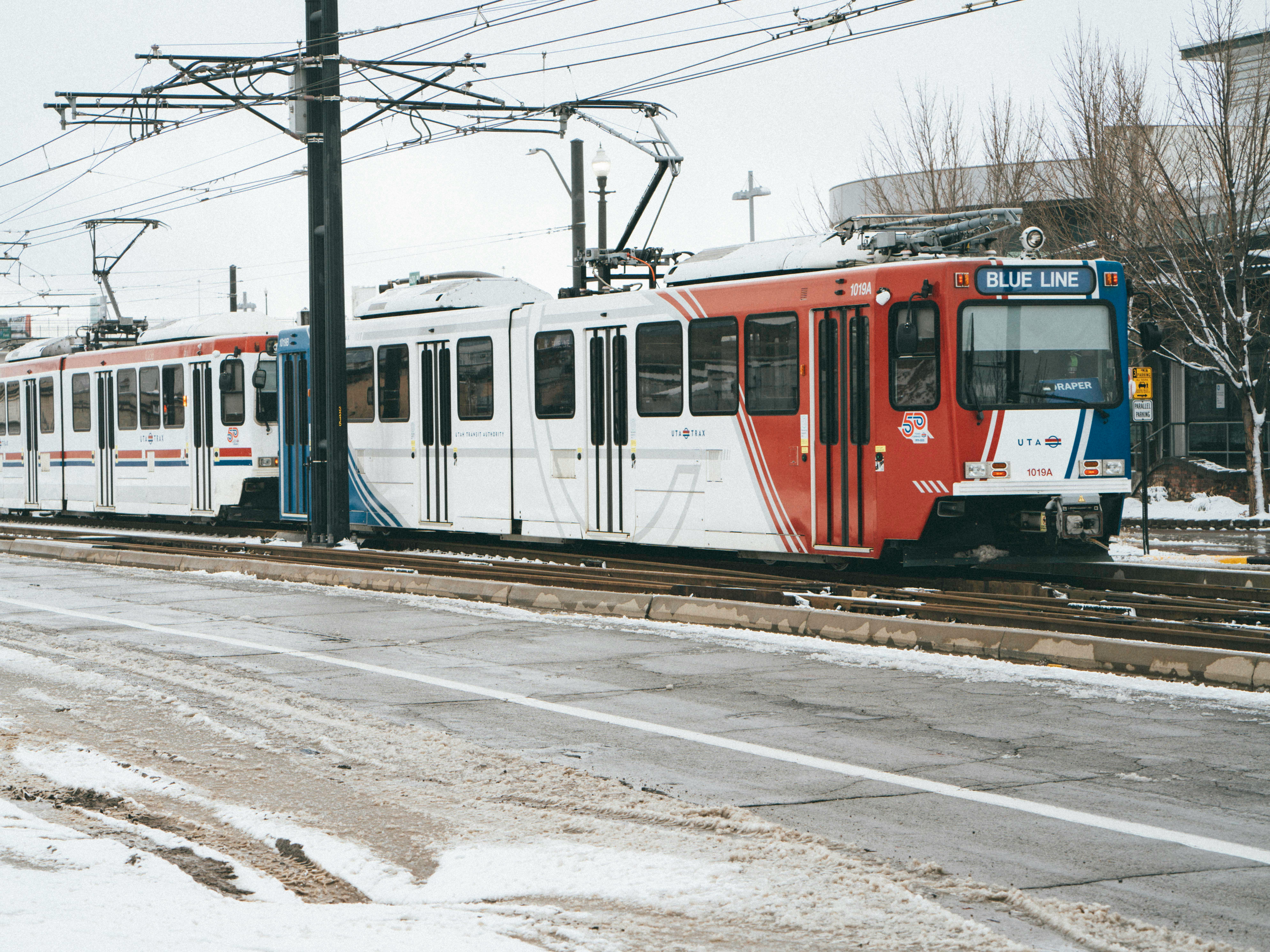 A train on the tracks near a snowy road in Salt Lake City, Utah.
