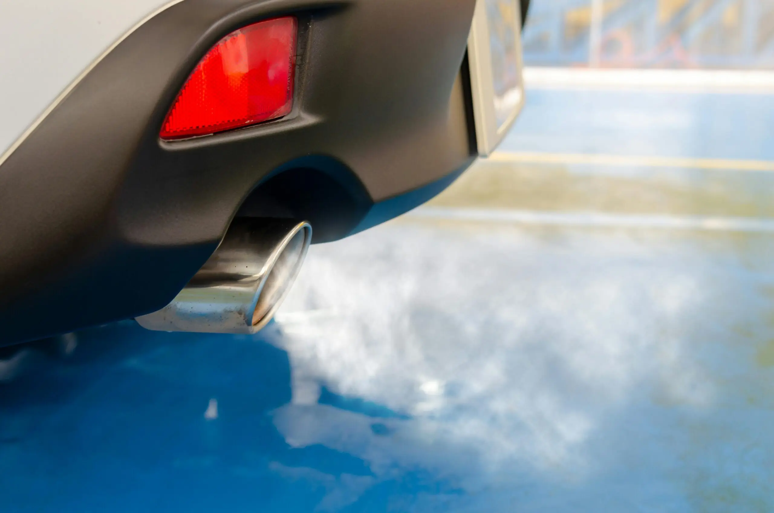 A silver vehicle's exhaust pipe emits greenhouse gases.
