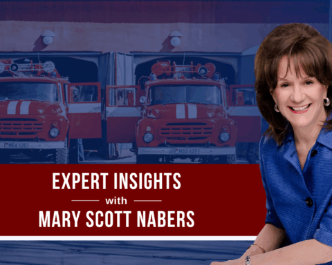 Mary Scott Nabers before fire trucks and a fire station for her weekly column.