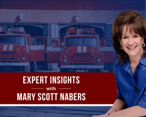 Mary Scott Nabers before fire trucks and a fire station for her weekly column.