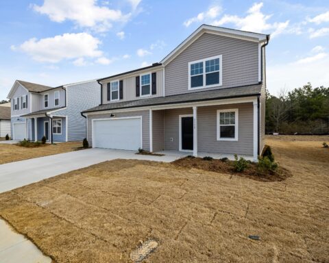 Suburban homes with newly installed grass before a wooded area.
