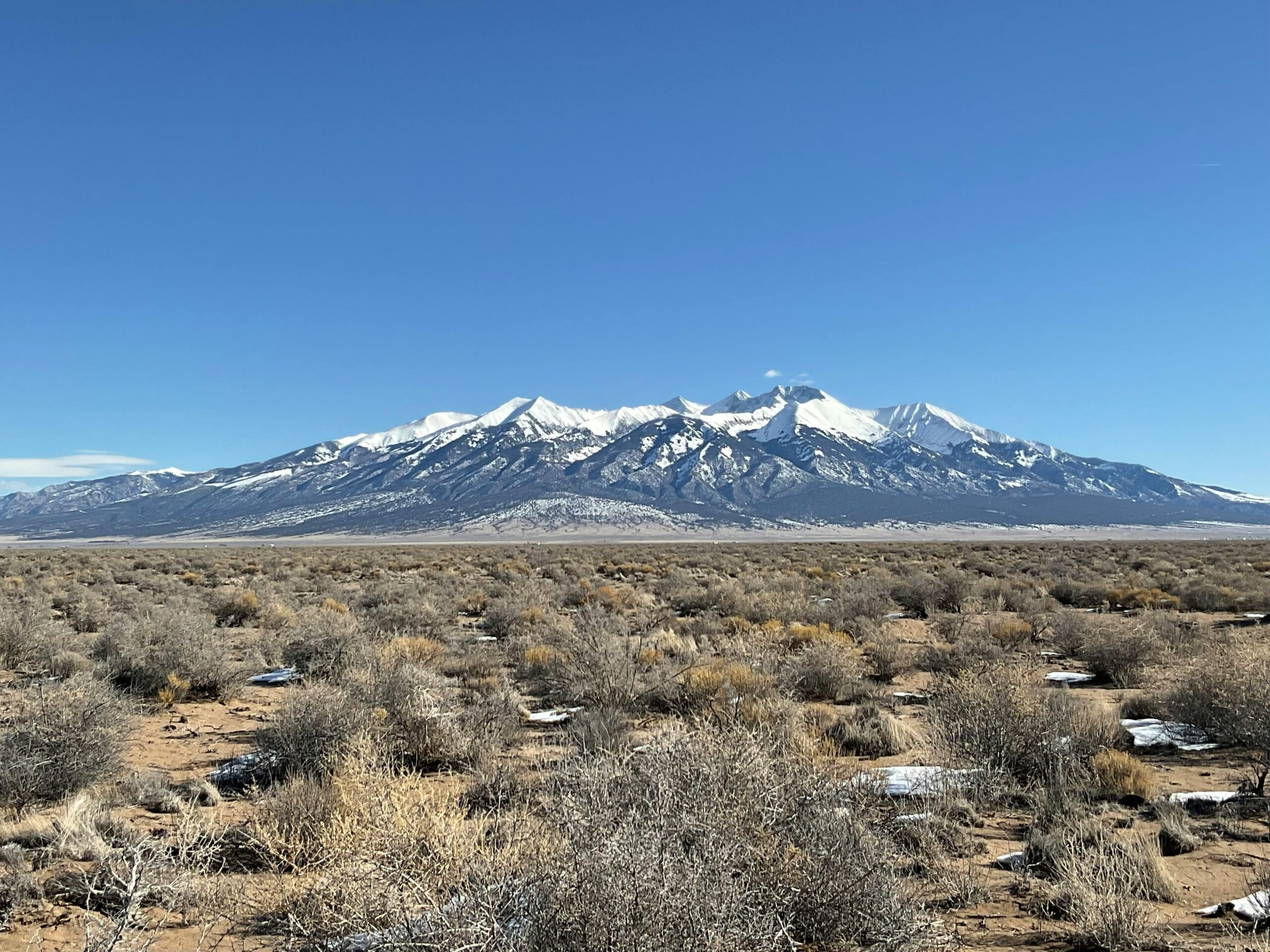 Desert sand dunes, dirt and grass in a field in Colorado's Alamosa County.