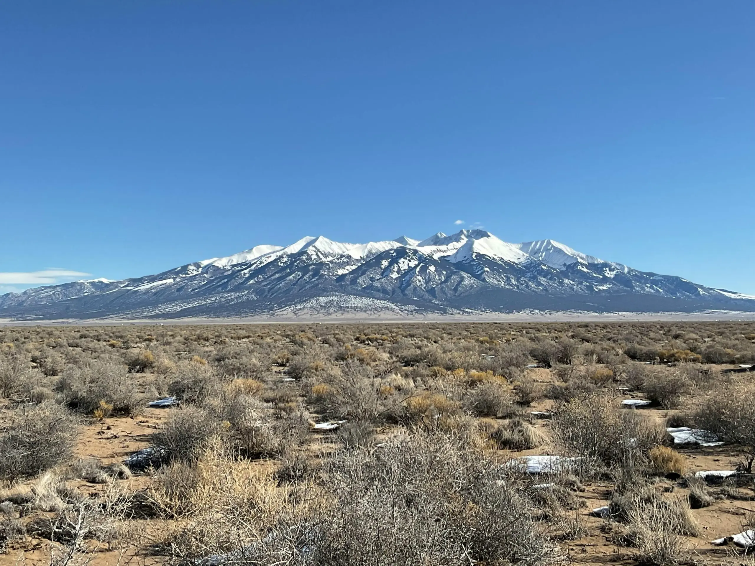 Desert sand dunes, dirt and grass in a field in Colorado's Alamosa County.