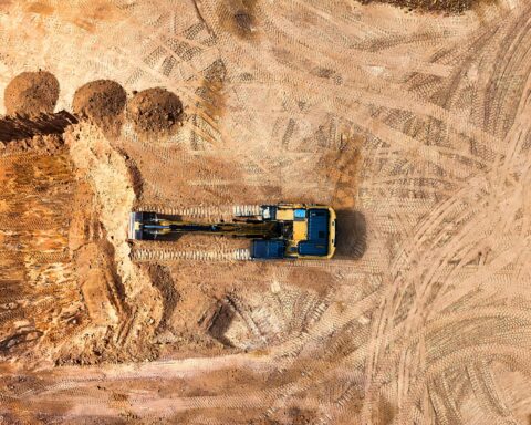 An excavator on a dirt job site from an aerial perspective.