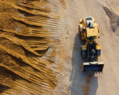 A construction vehicle on a work site next to a pile of dirt from an aerial perspective.