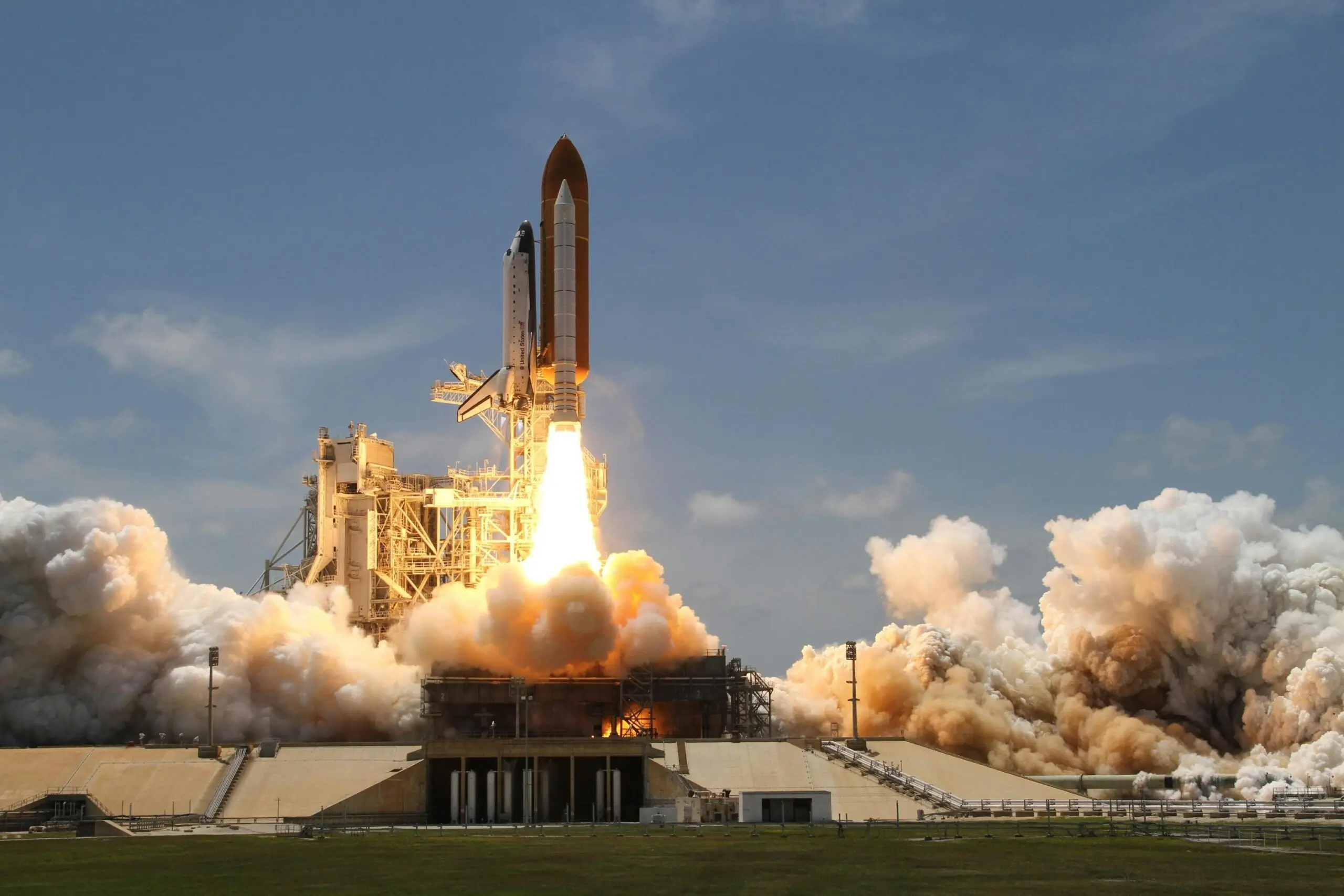 A rocket ship takes off with a fiery blast into a blue sky.