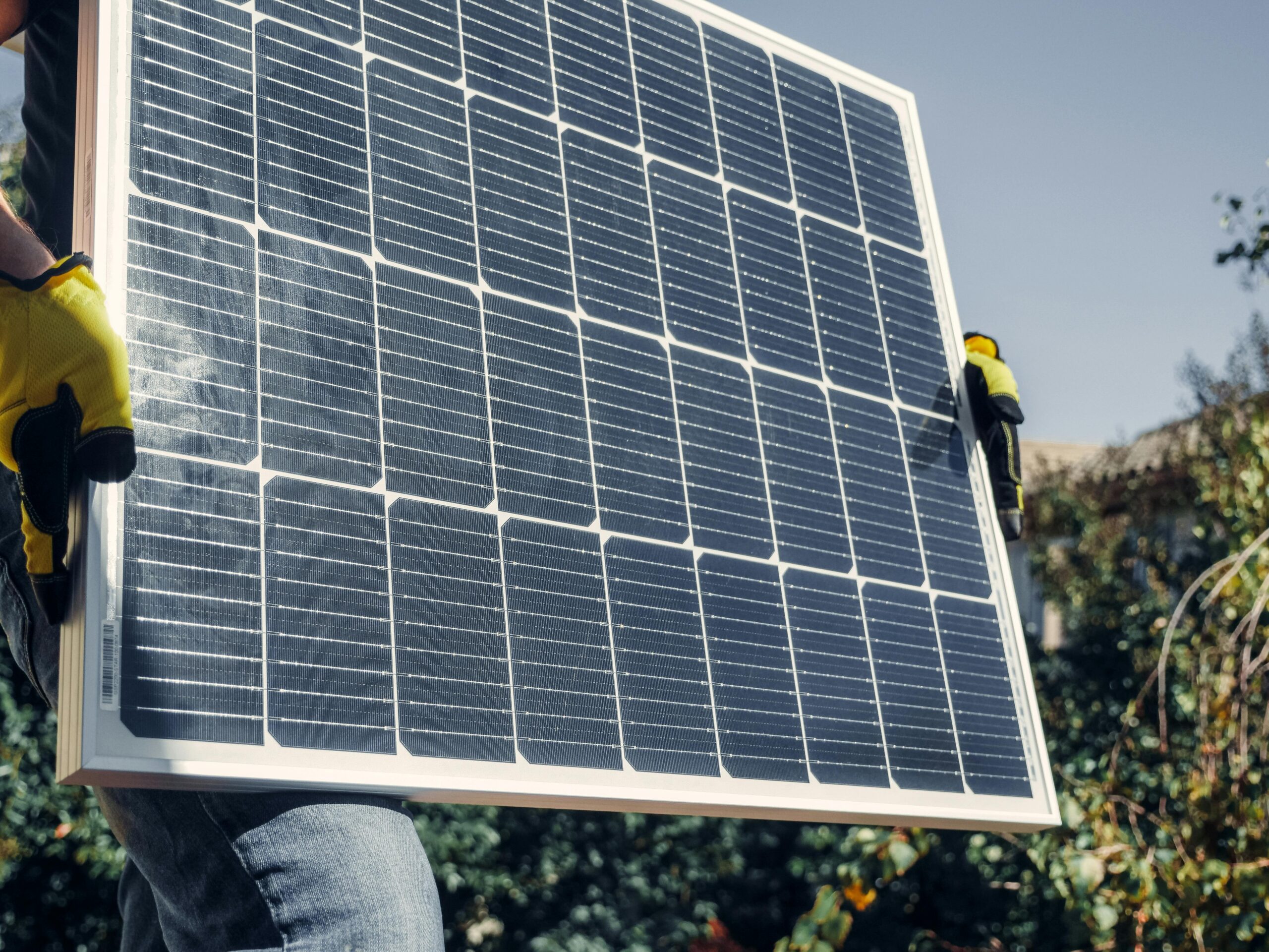 A construction worker carries a solar panel for installation.