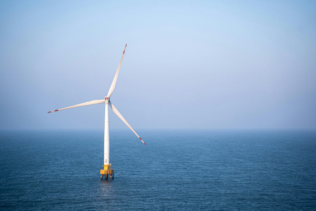 A solo wind turbine in the middle of a body of water.