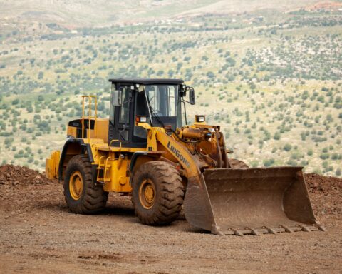 A construction vehicle on the edge of a dirt mound.