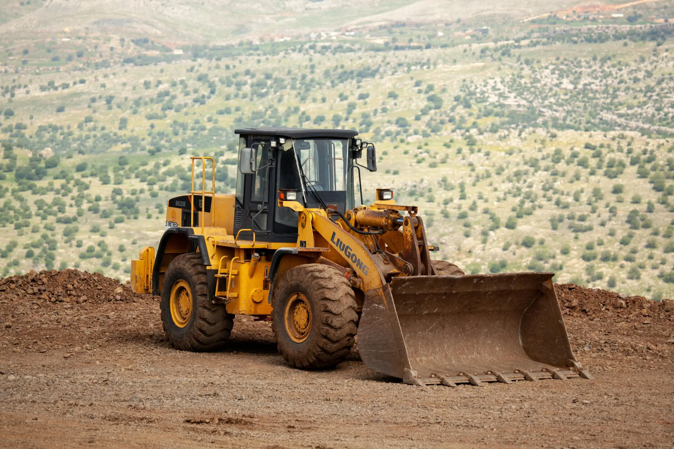 A construction vehicle on the edge of a dirt mound.