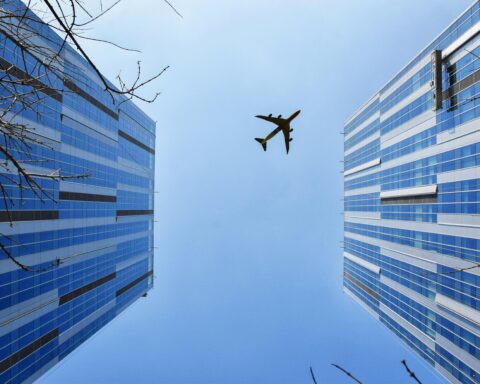 An airplane above two buildings from the ground.