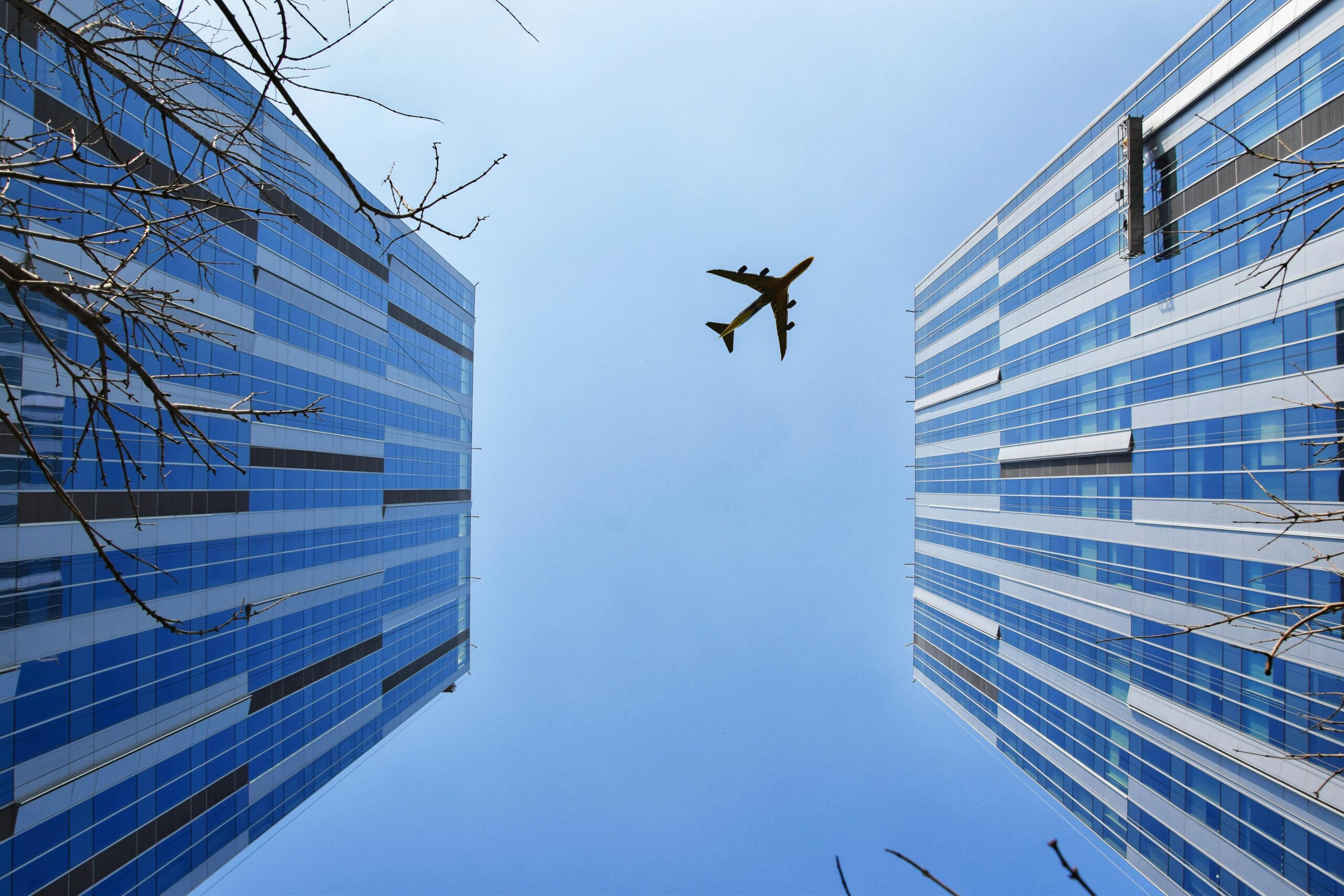 An airplane above two buildings from the ground.