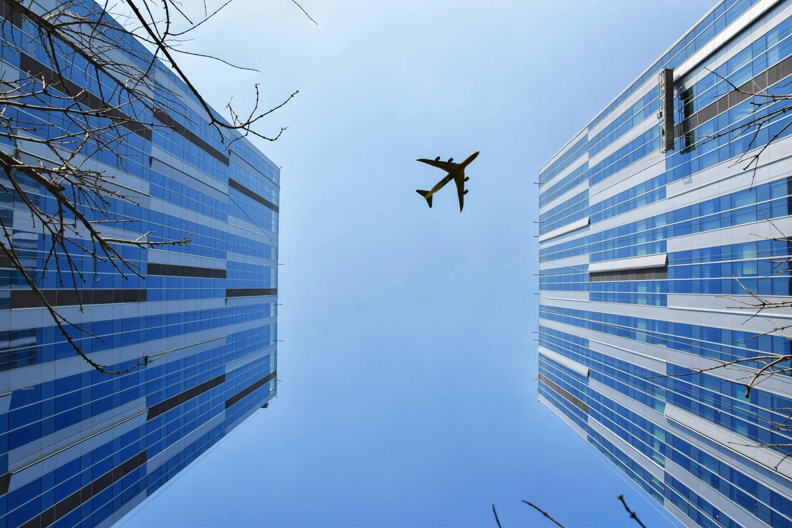 An airplane above two buildings from the ground.