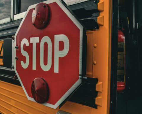 A stop sign on the side of a yellow school bus.