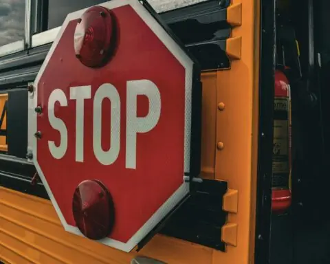 A stop sign on the side of a yellow school bus.
