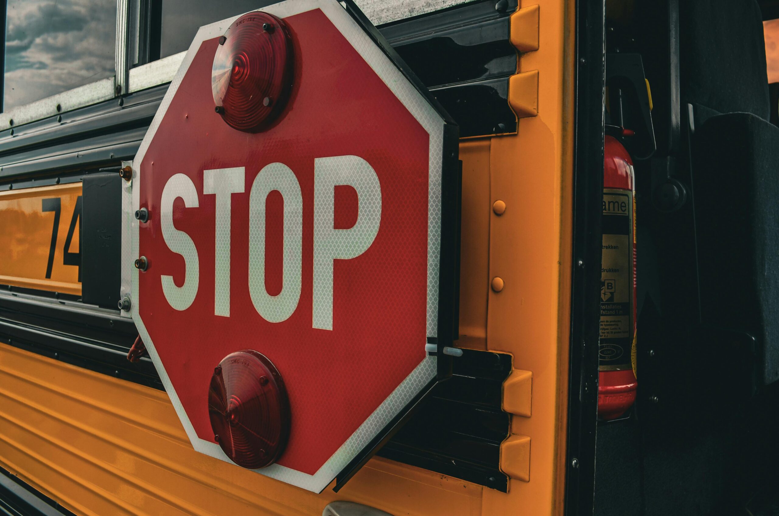 A stop sign on the side of a yellow school bus.