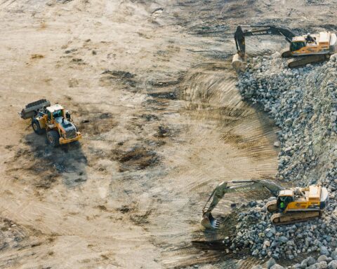 An aerial view of severel construction vehicles on a dirt site.