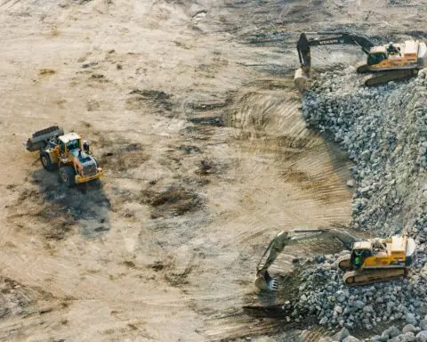 An aerial view of severel construction vehicles on a dirt site.