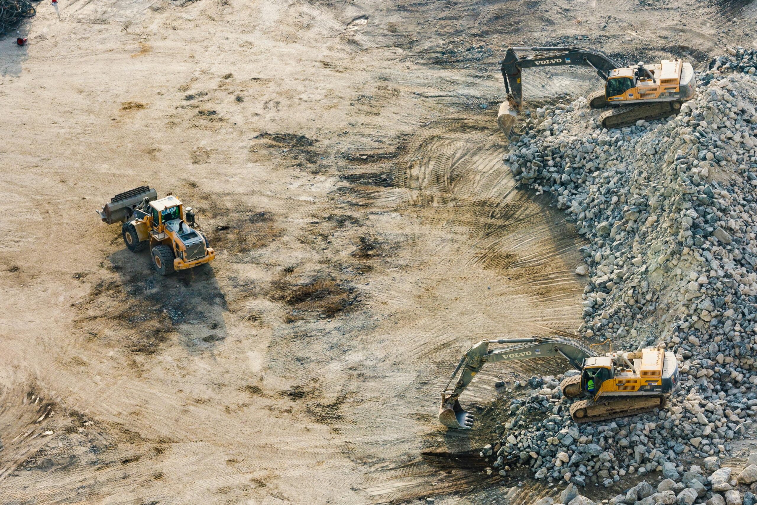 An aerial view of severel construction vehicles on a dirt site.