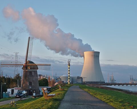 A nuclear power plant in Belgium alongside a nearby windmill and road.