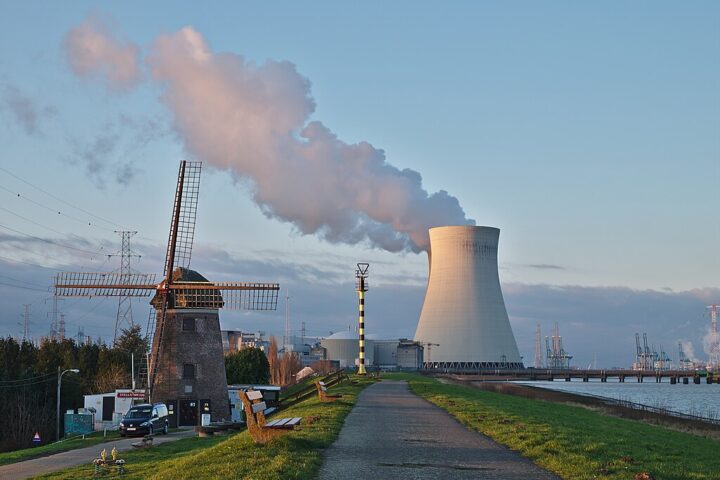 A nuclear power plant in Belgium alongside a nearby windmill and road.