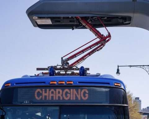 An electric bus connects to a charging station in New York.