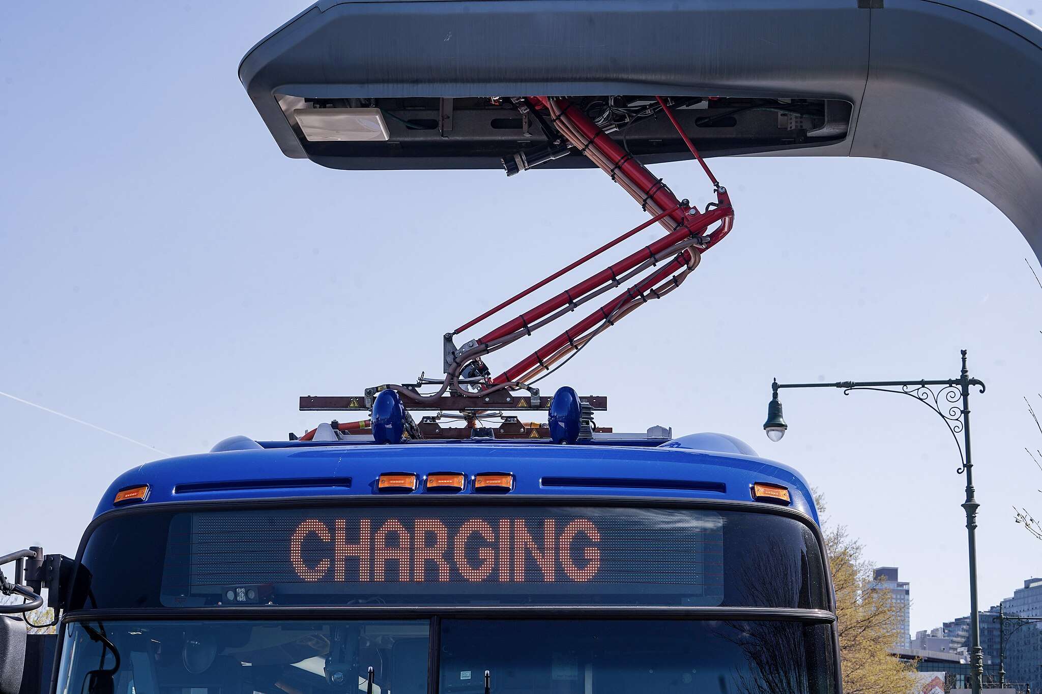 An electric bus connects to a charging station in New York.