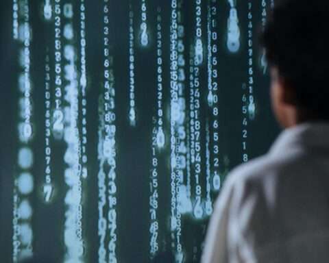 A man stands before a digitized wall with dropping code streaks.