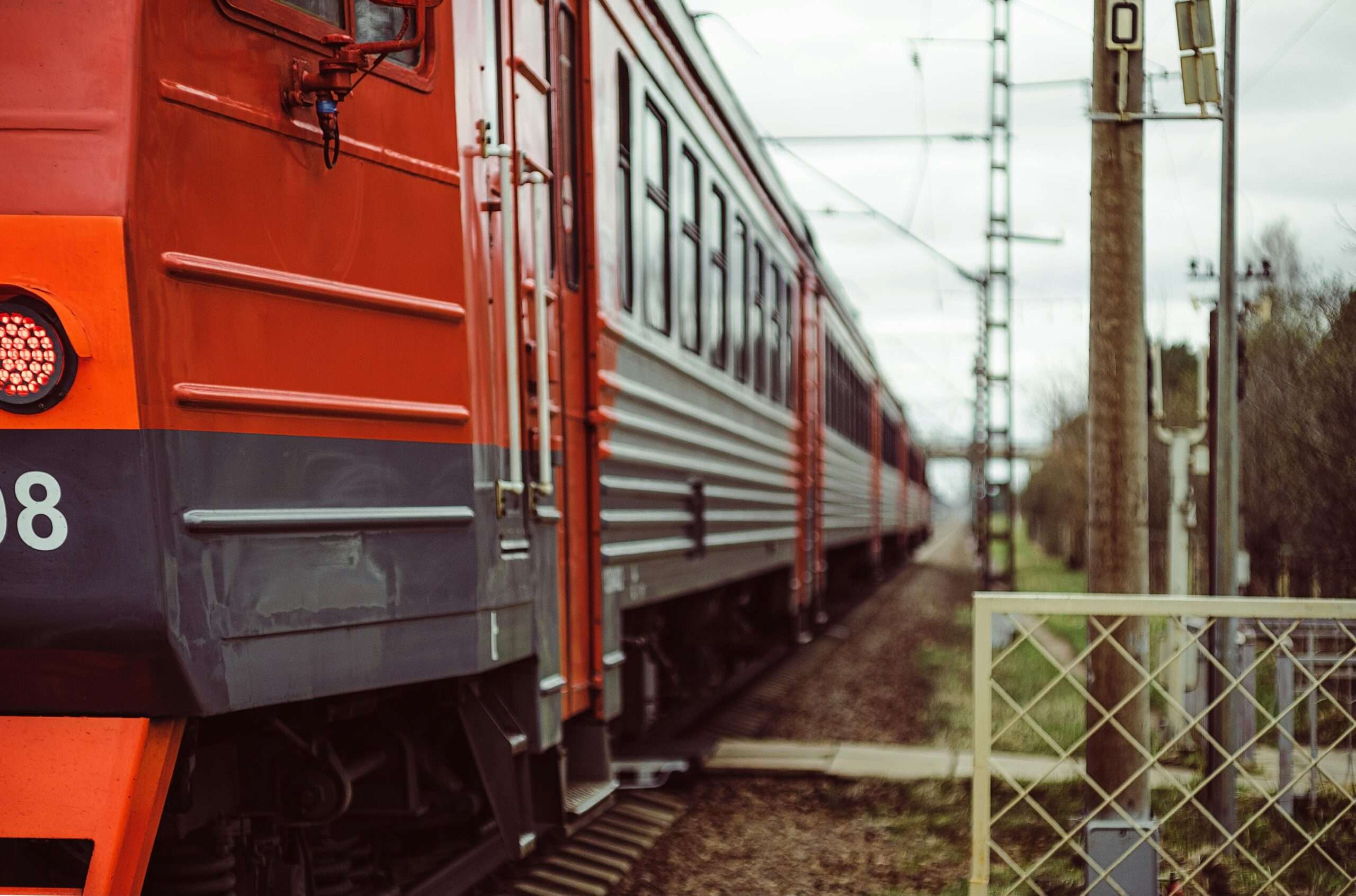 A red train sits on tracks nearby a railroad crossing.