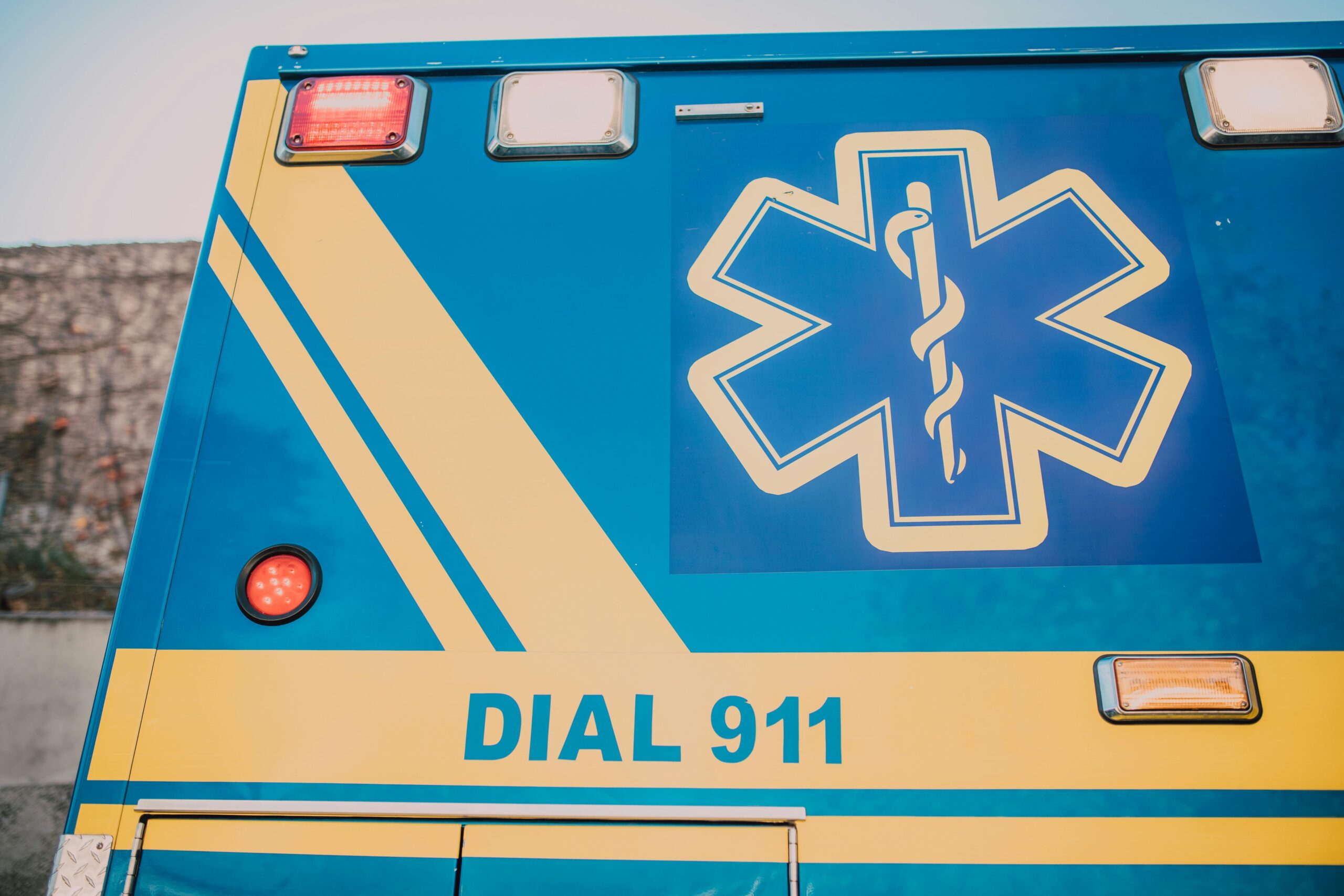 The side of an ambulance that says DIAL 911 alongside a medical system.
