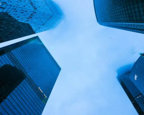 Skyscrappers raise into a deep blue cloudy sky.