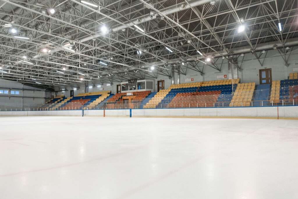 The inside of a hockey arena with colored seats and bright lights from ice level.