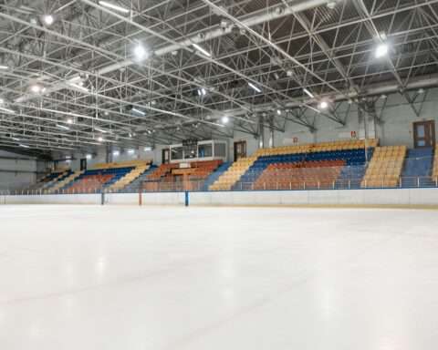 The inside of a hockey arena with colored seats and bright lights from ice level.