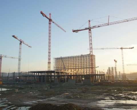 A large construction site with several cranes towering above the site.