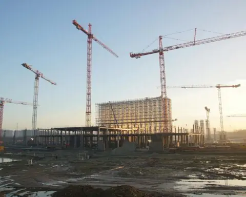 A large construction site with several cranes towering above the site.