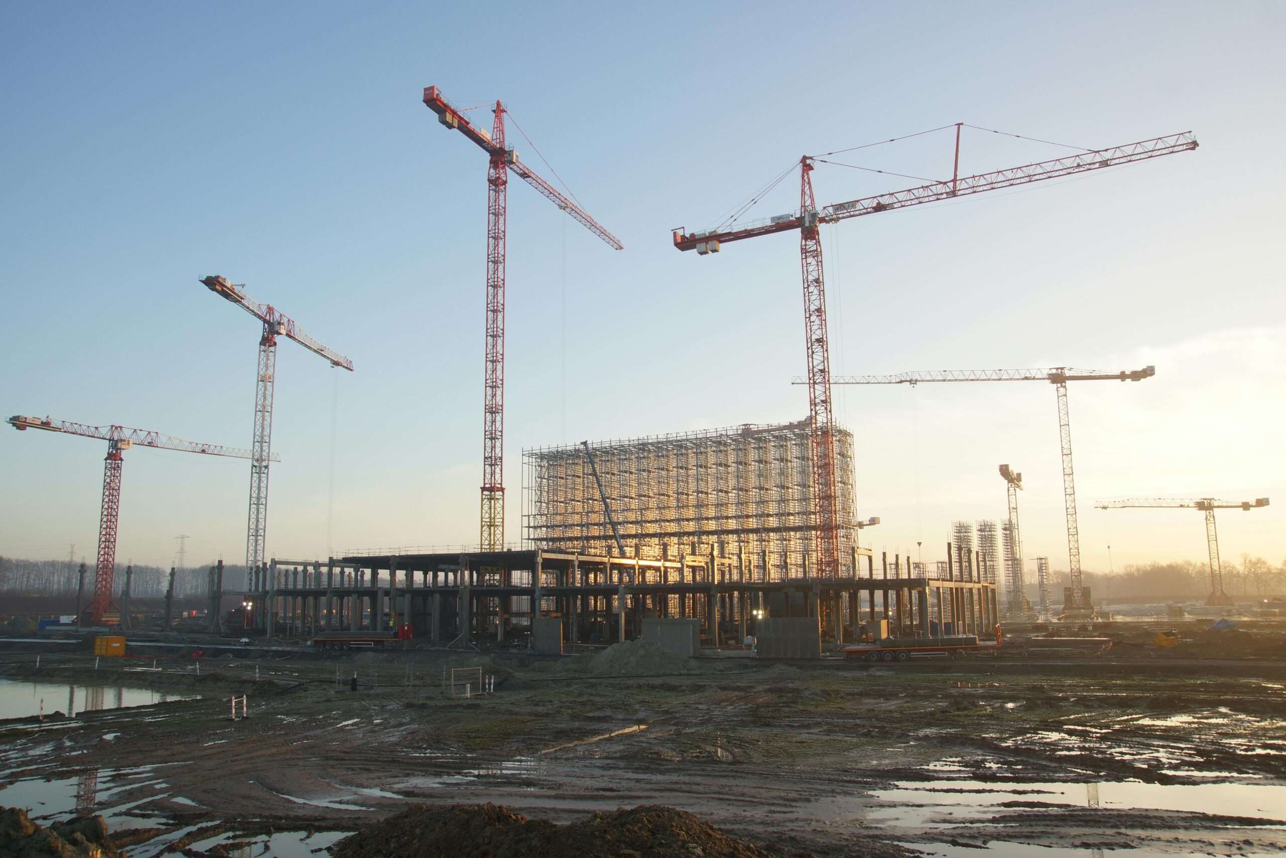 A large construction site with several cranes towering above the site.