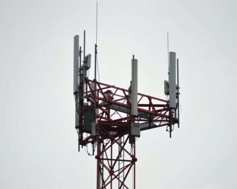 A 5G tower connecting residents and businesses to broadband internet service before a white cloudy sky.