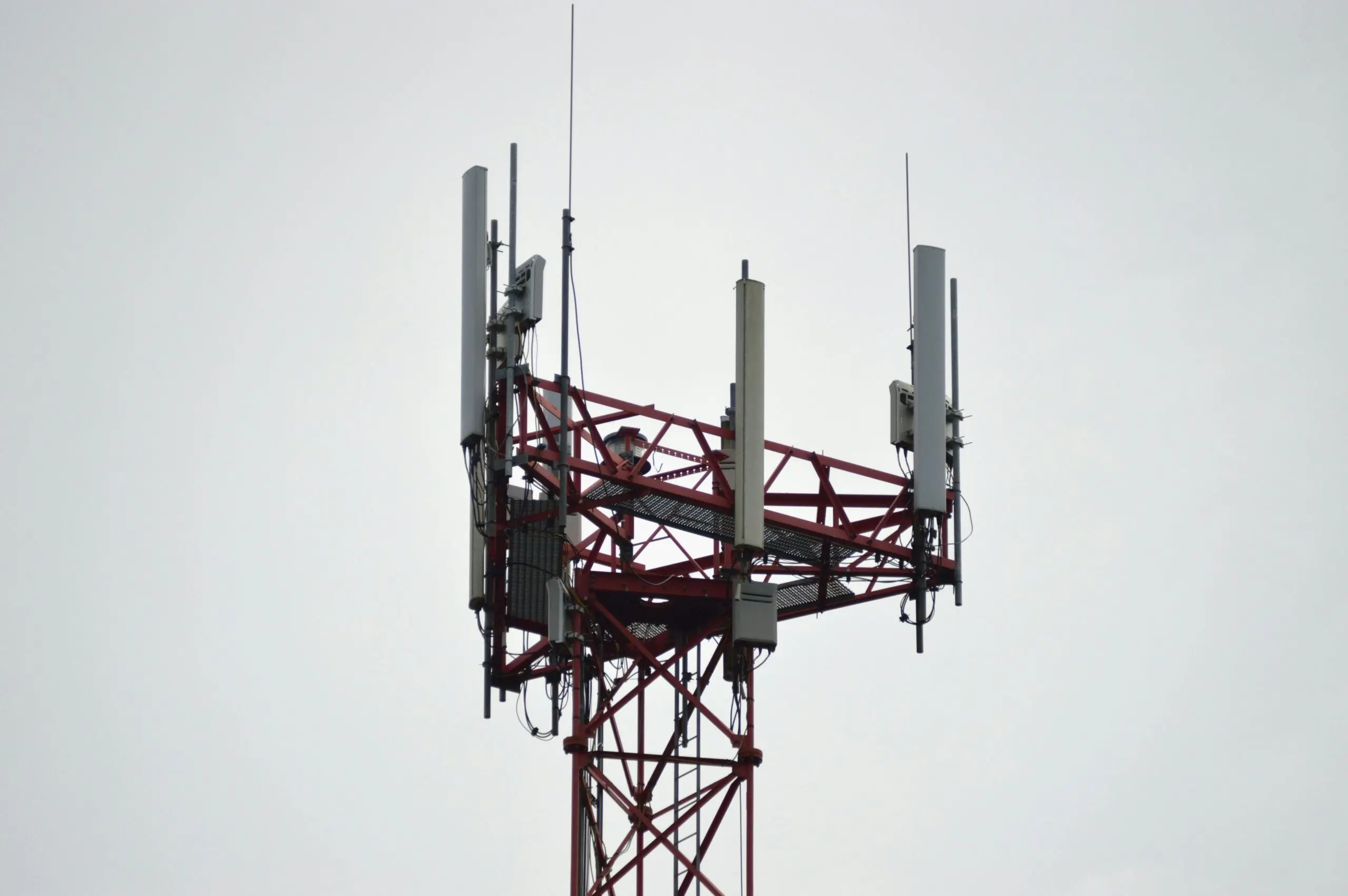 A 5G tower connecting residents and businesses to broadband internet service before a white cloudy sky.