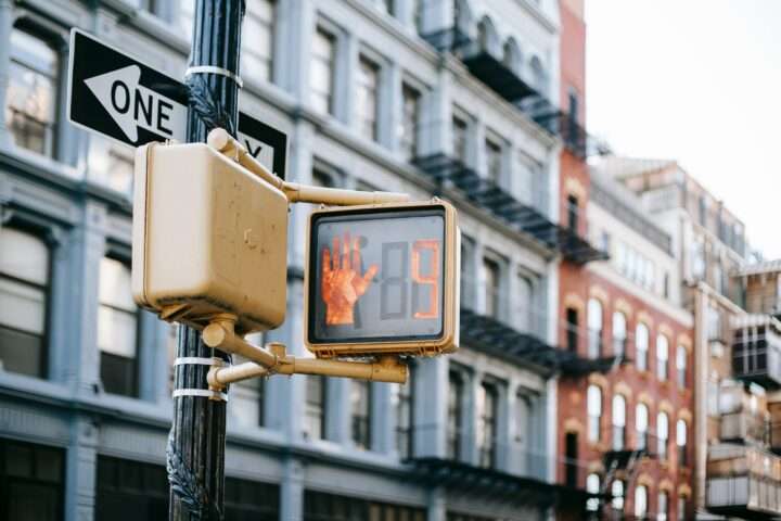 Digital signs on a traffic light along an intersection with residential housing building in the background.