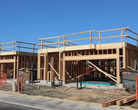 A housing development half-built before a blue sky and dirt.