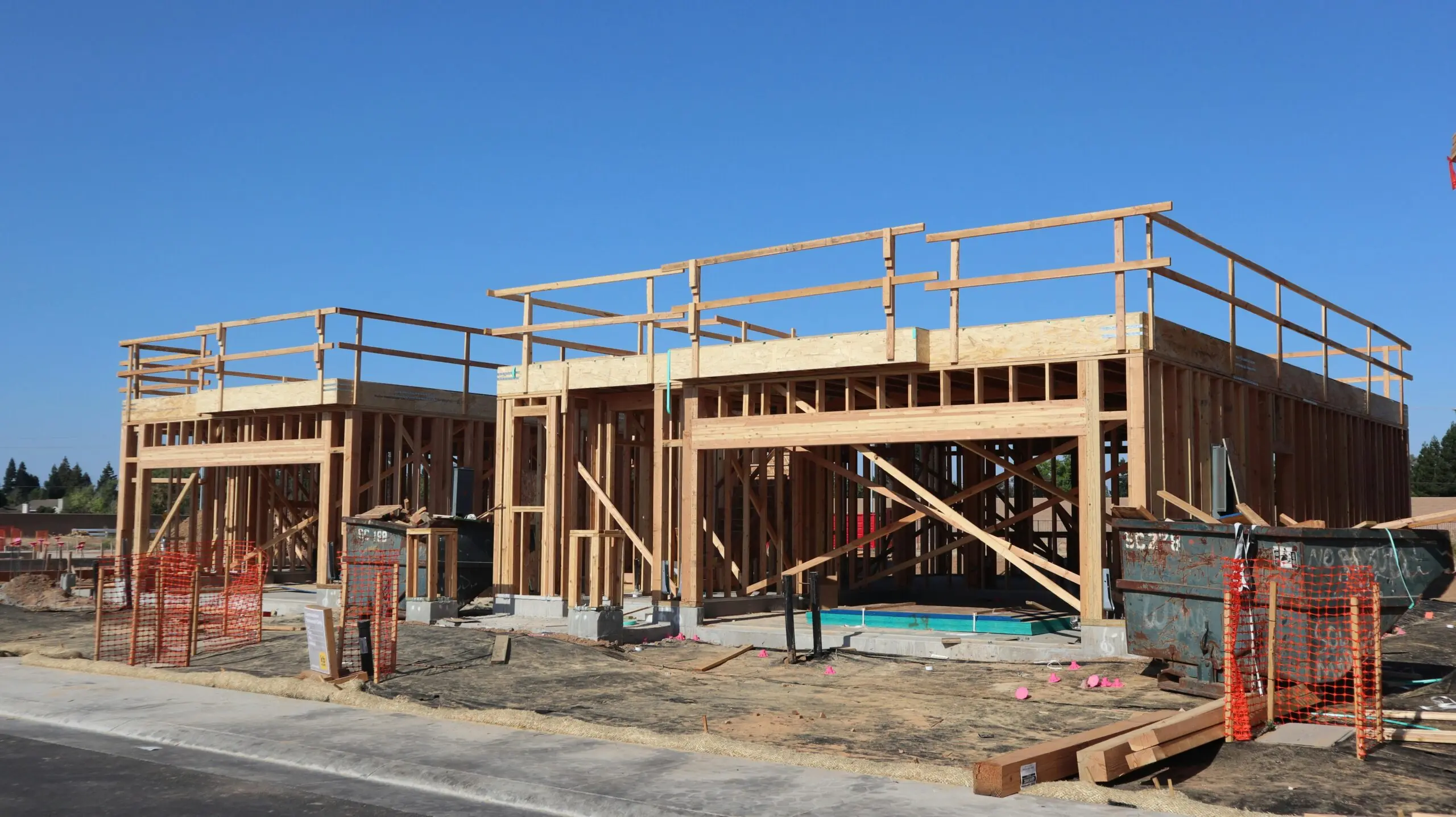 A housing development half-built before a blue sky and dirt.