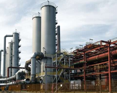 A coal-fired power plant from the ground before a cloudy blue sky.