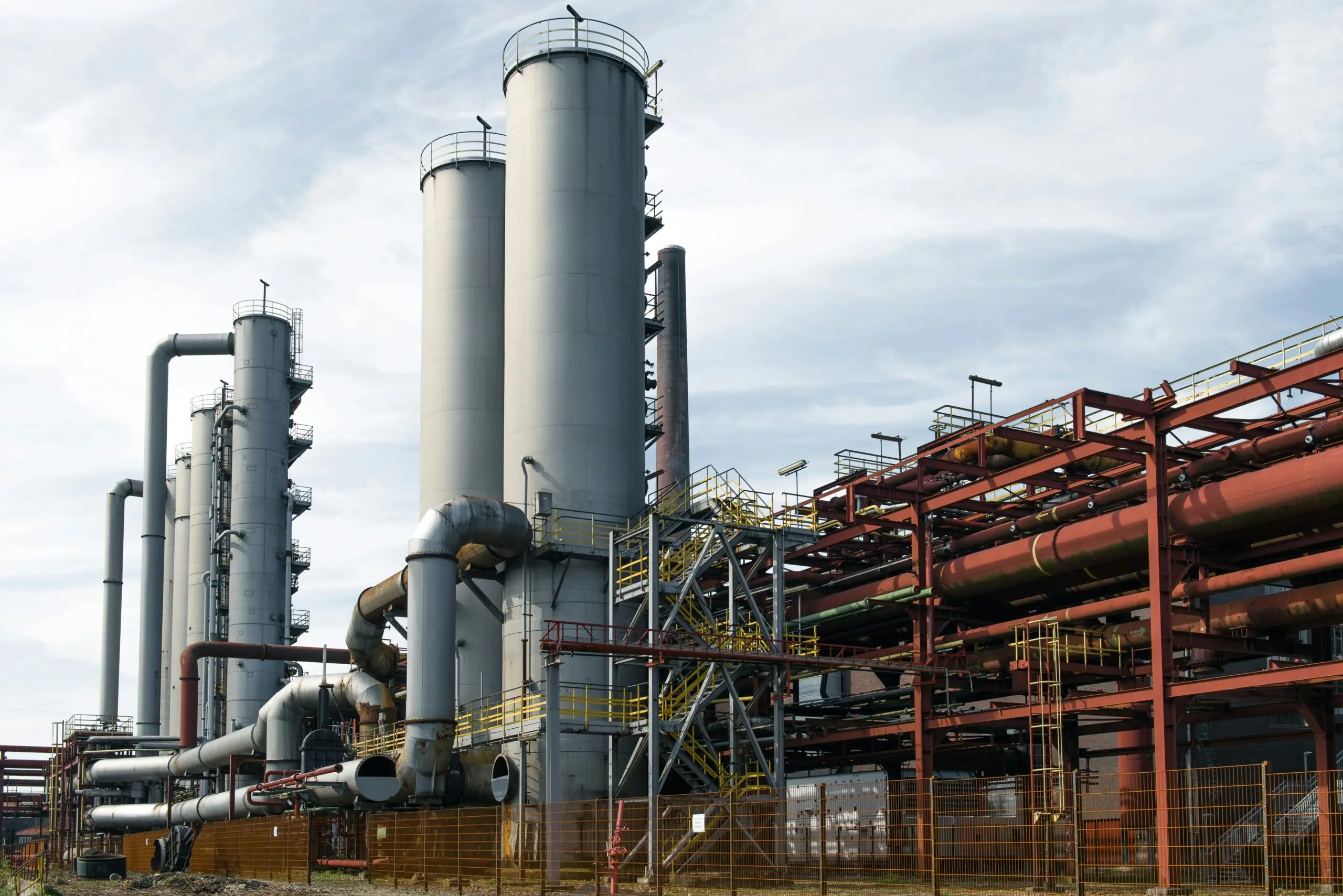 A coal-fired power plant from the ground before a cloudy blue sky.