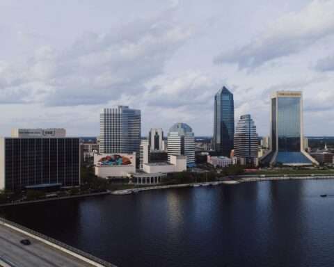 The Jacksonville skyline in Florida before a cloudy sky and a river.