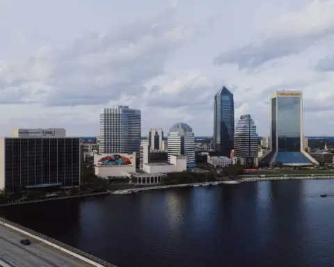 The Jacksonville skyline in Florida before a cloudy sky and a river.