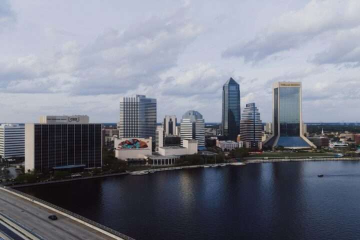 The Jacksonville skyline in Florida before a cloudy sky and a river.