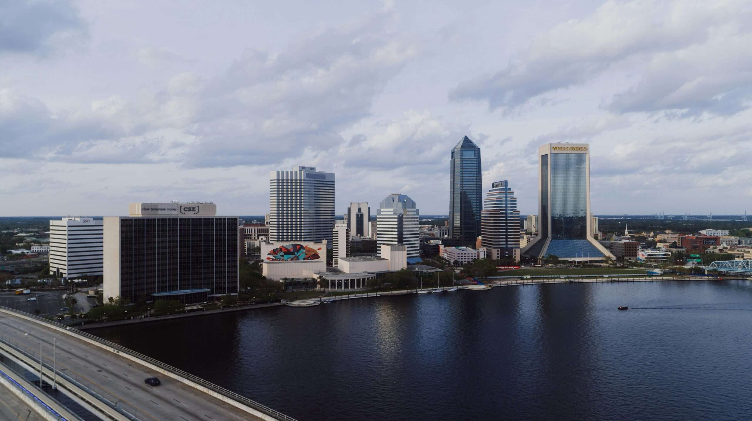 The Jacksonville skyline in Florida before a cloudy sky and a river.