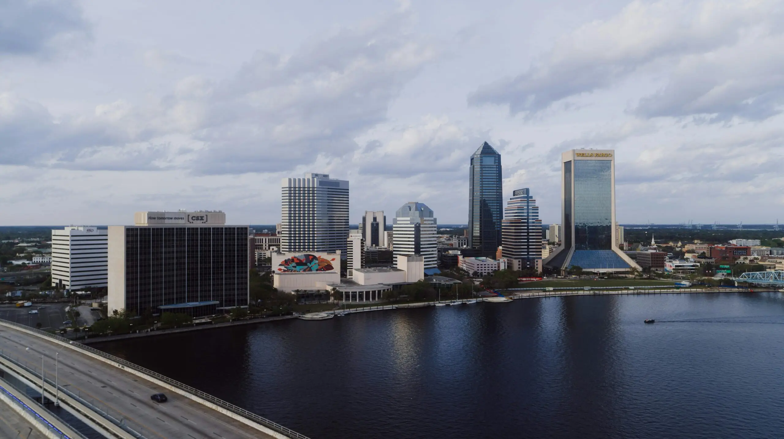 The Jacksonville skyline in Florida before a cloudy sky and a river.