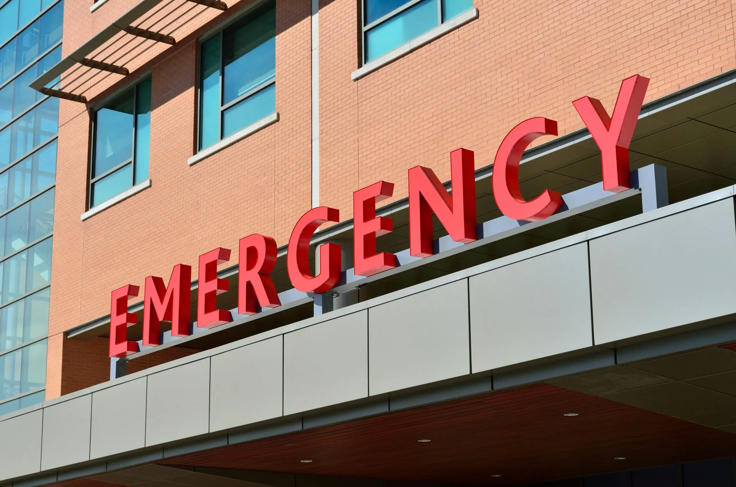 An emergency sign outside of a brick hospital during the day.